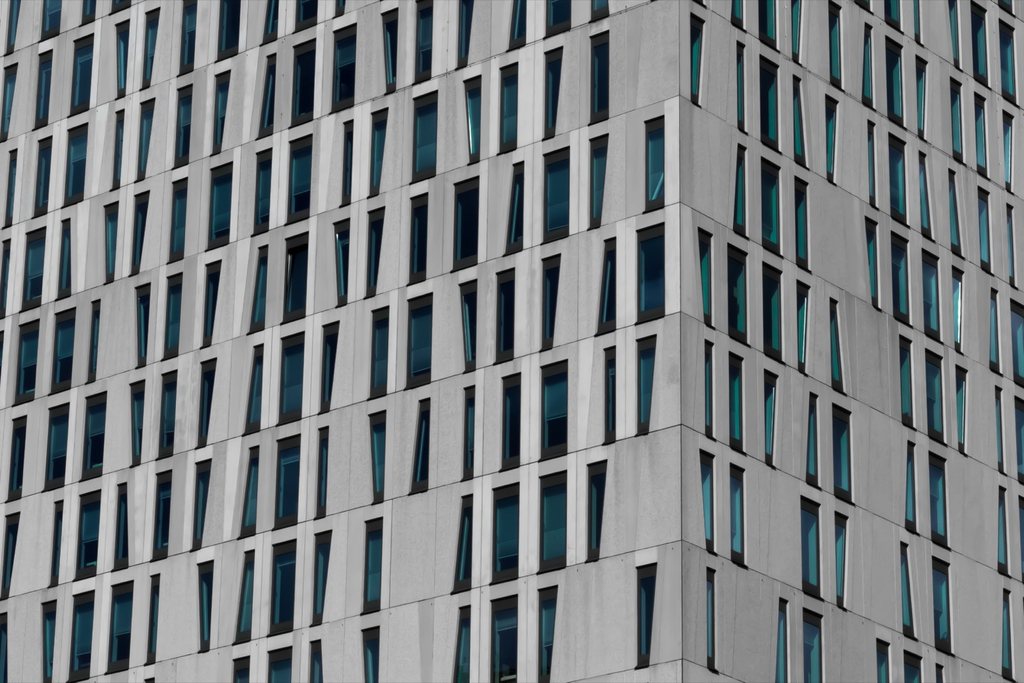 Structured grey office facade with repeated windows and disciplined vertical rhythm.
